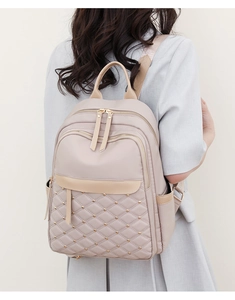 Rear view of a model wearing the beige quilted nylon backpack with gold rivet details