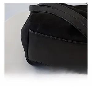 Detailed close-up of precise stitching on black suede and leather tote bag surface