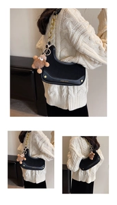 Détail du sac croissant noir avec chaîne dorée et breloque ours en peluche