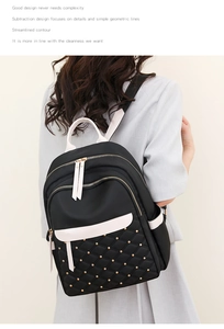 Detail of black quilted nylon backpack featuring white contrast straps and gold rivets