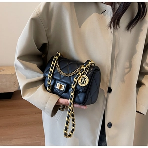 Detailed view of black quilted leather shoulder bag with gold chain and round charm