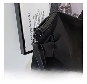 Close-up of gunmetal grey hardware hooks on a black minimalist tote bag with matte texture