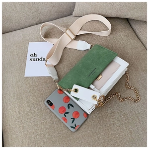 Détail d'un sac en cuir blanc avec rabat en daim vert et chaîne dorée chic