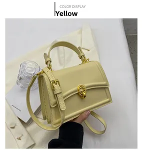 Detail of yellow leather handbag with gold ring lock and adjustable shoulder strap