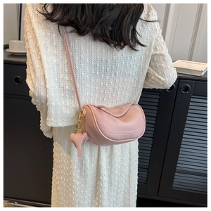 Detail of pink dumpling crossbody bag with lychee texture and heart charm on model