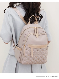 Detail of light apricot quilted nylon backpack featuring golden rivet accents and zippers