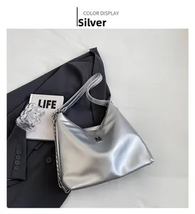 Detail of silver metallic handbag featuring metal M logo and chain strap on gray blazer