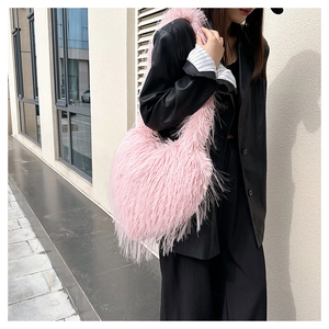 Close-up of pink faux fur heart-shaped shoulder bag worn with a black leather jacket
