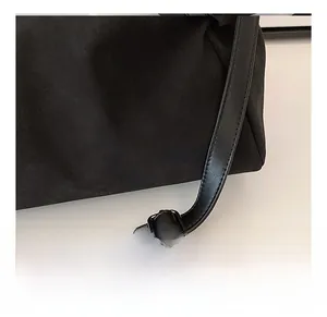 Close-up of adjustable leather shoulder strap with silver buckle on black suede tote bag