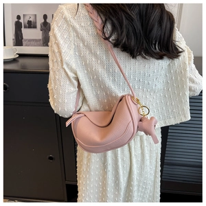 Pink crescent crossbody bag detail with textured leather, knotted flap and elephant charm