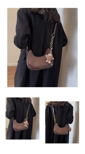 Détail du sac croissant marron foncé avec chaîne dorée et peluche accessoire