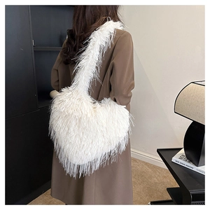 Detailed texture of white heart-shaped plush bag with fluffy feather fringes worn by model