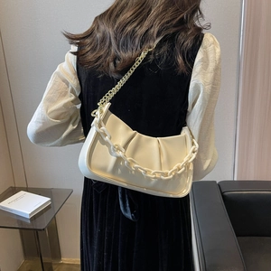 Chic beige cloud bag with pleated design and chunky chain strap shown on a model