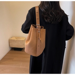 Détail de la bandoulière réglable et boucle argentée sur un sac seau marron mat