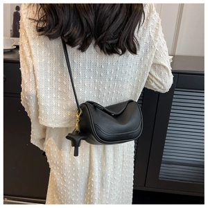 Close-up of black lychee grain leather crossbody bag with horse charm on a model
