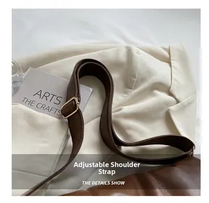 Détail du sac en cuir marron foncé montrant la bandoulière réglable et la boucle dorée