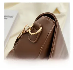 Detail view of the golden metal lobster clasp and D-ring on the brown leather crossbody bag