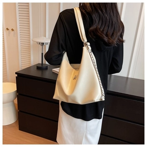 Detail view of a large cream hobo bag with a metallic M logo and chain strap detail