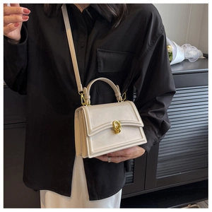 Detail of elegant beige crossbody bag with gold circular clasp and adjustable strap