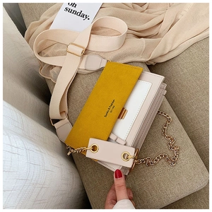 Détail du sac bandoulière avec rabat en daim jaune et corps en cuir beige et chaîne