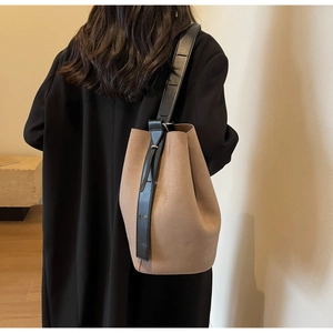 Sac seau en daim marron givré avec bandoulière noire porté à l'épaule par un mannequin