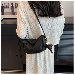 Detail of black lychee grain leather dumpling bag with woven strap and gold ring hardware