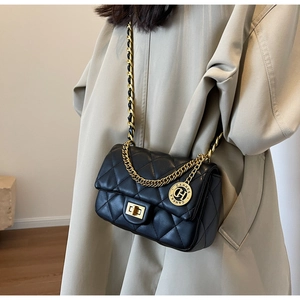 Detail of black quilted shoulder bag with gold chain strap and metallic brand tag