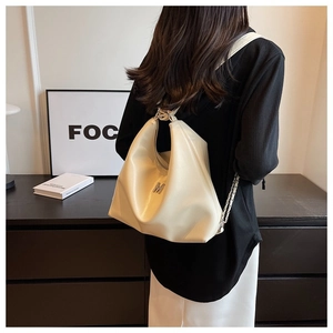 Detail of cream hobo bag with silver M logo and chain strap worn by a model