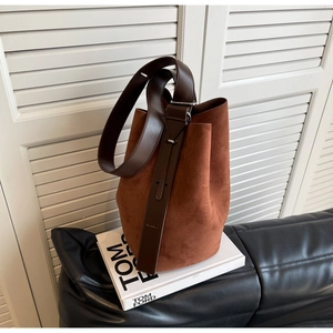 Détail de la boucle de bandoulière réglable sur le sac seau en cuir mat caramel