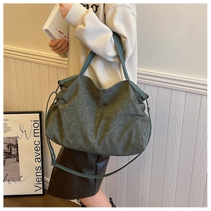 Detail of large dark teal tote bag with matte texture shown on model for daily commute
