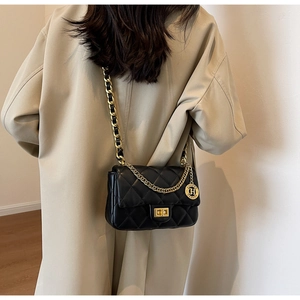 Detail of black quilted shoulder bag with gold metal twist lock and chain strap