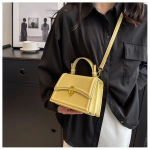 Detail of elegant beige crossbody bag with gold twist lock and smooth leather texture