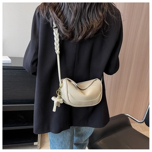 Detail of oatmeal leather half-moon crossbody bag with woven strap and elephant charm
