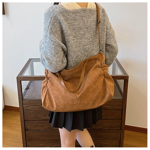 Detail of dark brown large tote bag with side pleats and adjustable shoulder strap