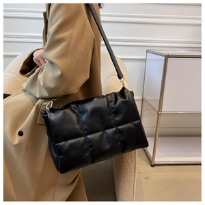 Gros plan d'un sac à bandoulière matelassé noir en cuir brillant avec détails dorés en métal