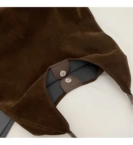 Detail view of the magnetic snap closure and suede texture of the dark brown tote bag