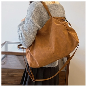 Detail of a large brown matte tote bag with vintage pleats and adjustable shoulder strap