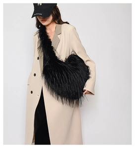 Detail of oversized black faux fur crossbody bag styled with a minimalist wool coat