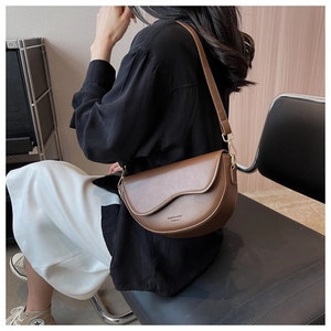 Detail of a dark brown crescent bag showing the matte PU leather texture and shoulder strap