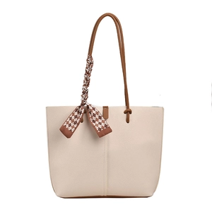 Minimalist beige quilted tote bag with brown handles and a checkered silk scarf accessory