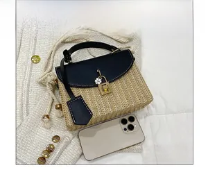 Détail d'un sac à main en paille tressée avec rabat en cuir noir et fermoir doré chic