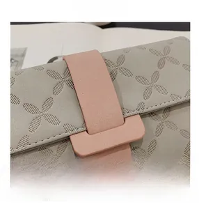 Gros plan du portefeuille long gris avec fermoir rose et texture florale gaufrée