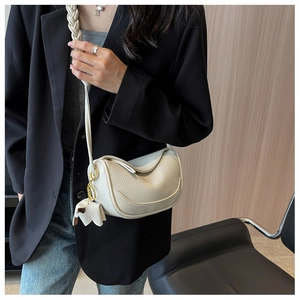 Detail of cream hobo bag with lychee texture, braided strap and horse charm on model