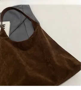 Close-up of brown suede tote bag featuring matte texture and smooth leather straps