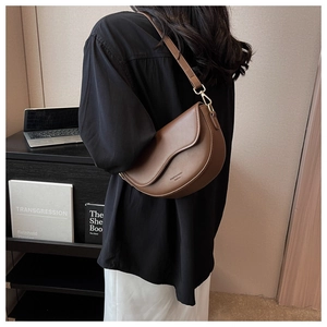 Detail view of a vintage brown saddle bag with wave flap design and gold buckle
