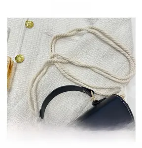 Détail du sac de selle en cuir noir avec bandoulière tissée blanche réglable