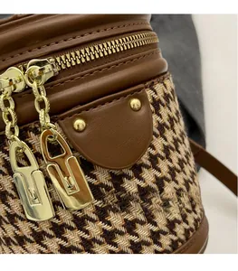 Close-up of houndstooth fabric with brown leather trim and gold double zipper hardware