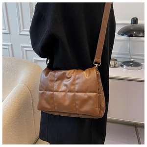 Sac bandoulière marron matelassé avec sangle réglable et détails dorés porté par modèle
