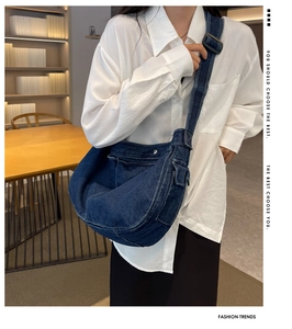 Detail of a dark blue denim messenger bag with side pocket and wide adjustable strap