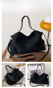 Detail of black suede tote bag showing soft matte texture and leather shoulder straps